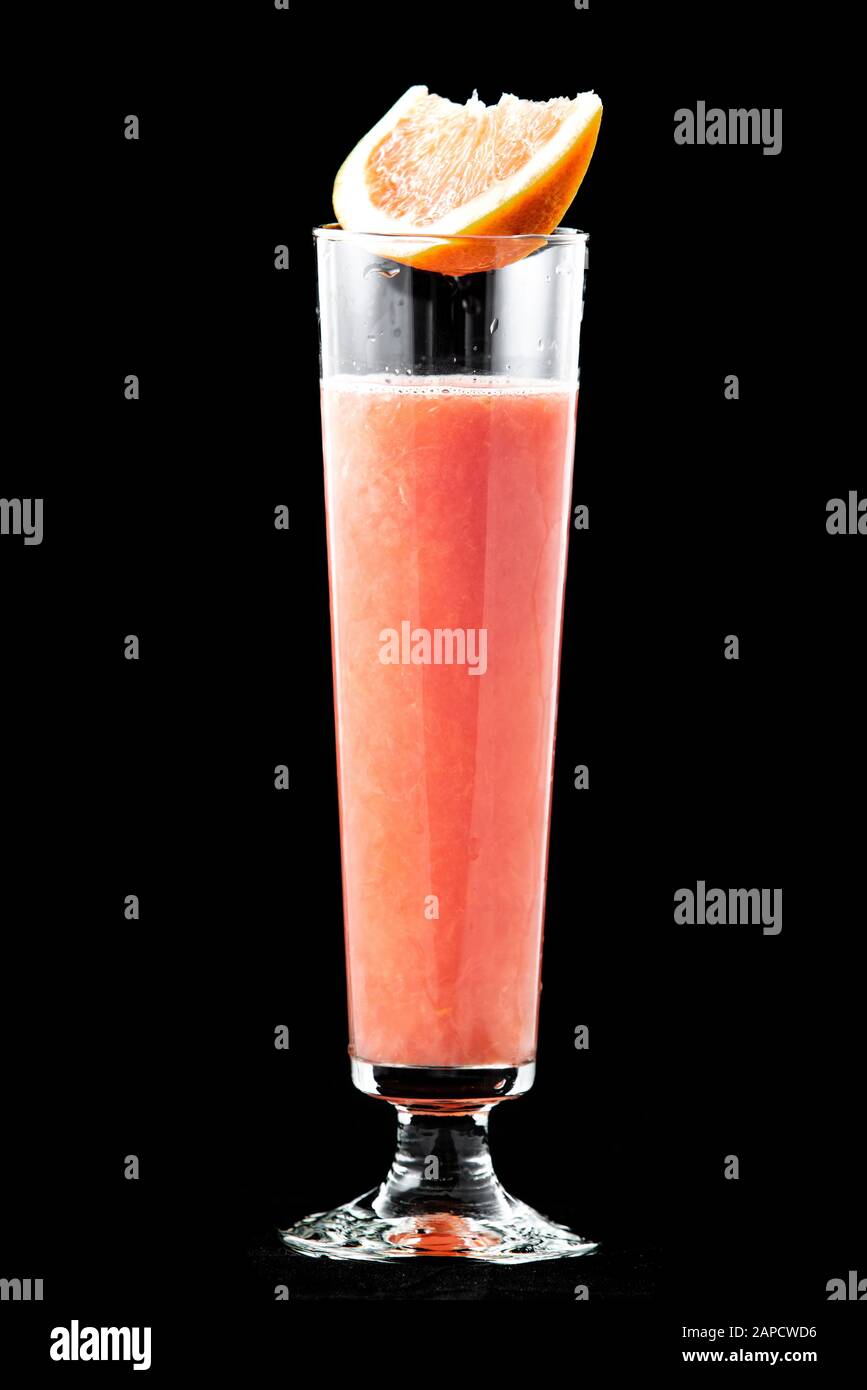 Frisch gepresster Grapefruitsaft in einem Glas, oben auf dem Glas ist eine Scheibe frische Grapefruit. Isoliert auf schwarzem Hintergrund. Stockfoto