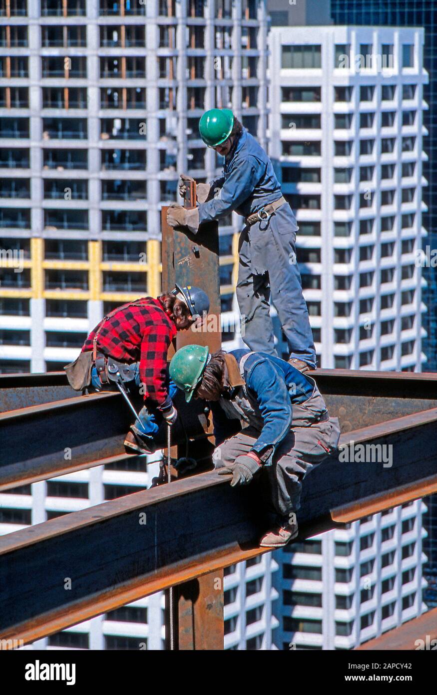 Bauarbeiter auf eisernen Balken, die hoch oben auf einem Büroturm arbeiten Stockfoto