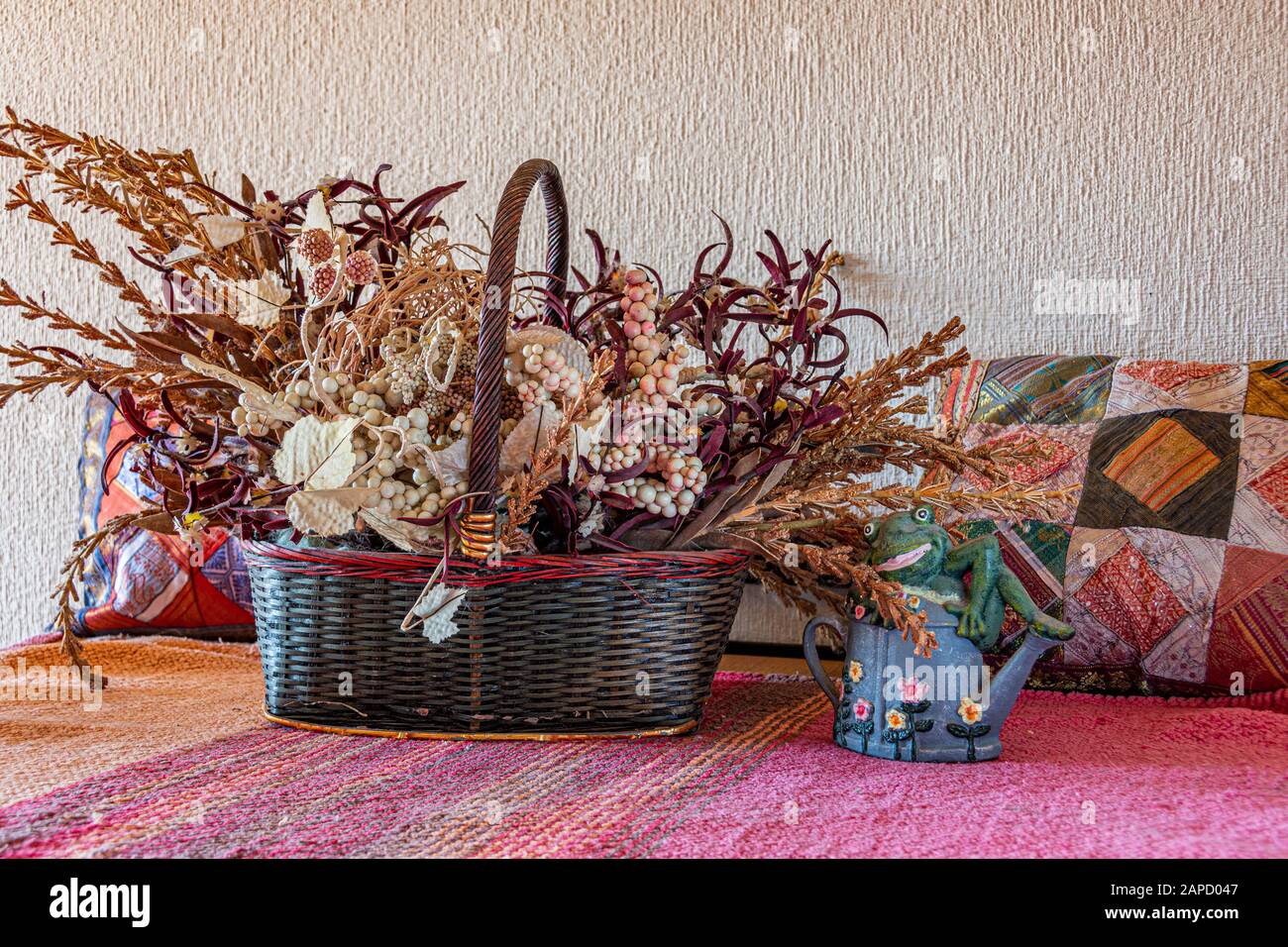 Bildkomposition Gemüsekorb polstert Teekanne und Frosch im rustikalen Genre. Stockfoto