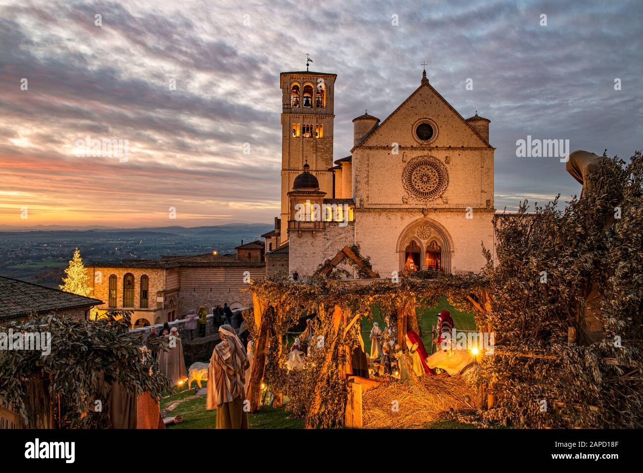 Assisi, Perugia, Umbrien, Italien. Die majestätische Kirche San Francesco, in der der Heilige begraben ist, bei Sonnenuntergang, mit der Krippe draußen während Weihnachten Stockfoto
