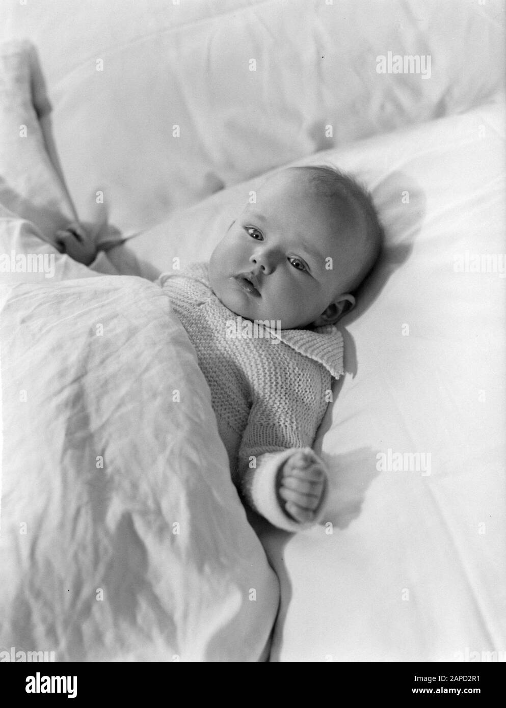 Agnes liegt in einem großen Bett Datum: 1934 Schlüsselwörter: Babys, Betten, Kleidung, Mädchen, Pflege persönlicher Name: Flines, Agnes de Stockfoto