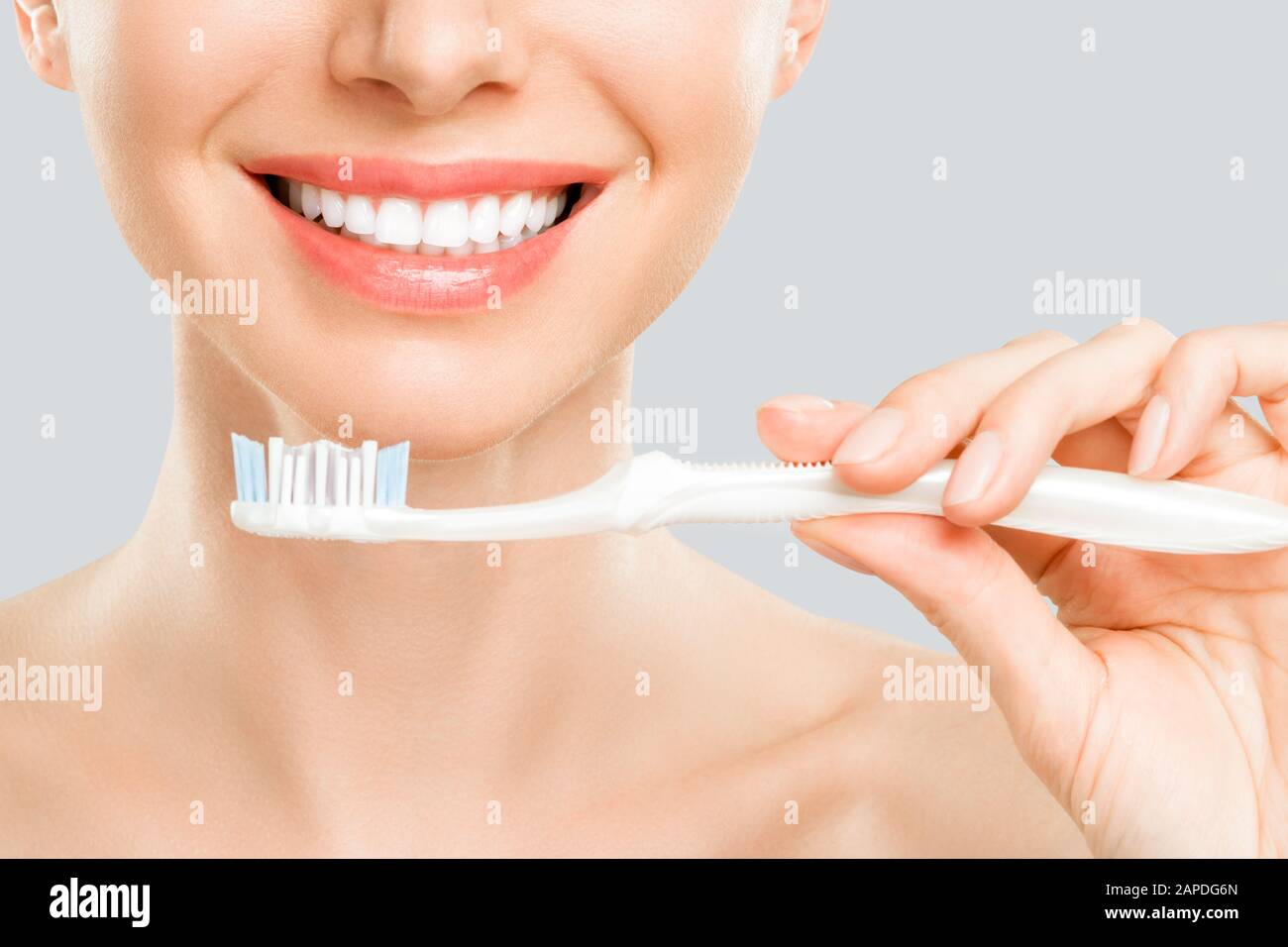 Wunderschöne lächelnde Frau Reinigung ihrer Zähne mit der Zahnbürste in einem Dental-Hygiene-Konzept. Isoliert auf weiss Stockfoto