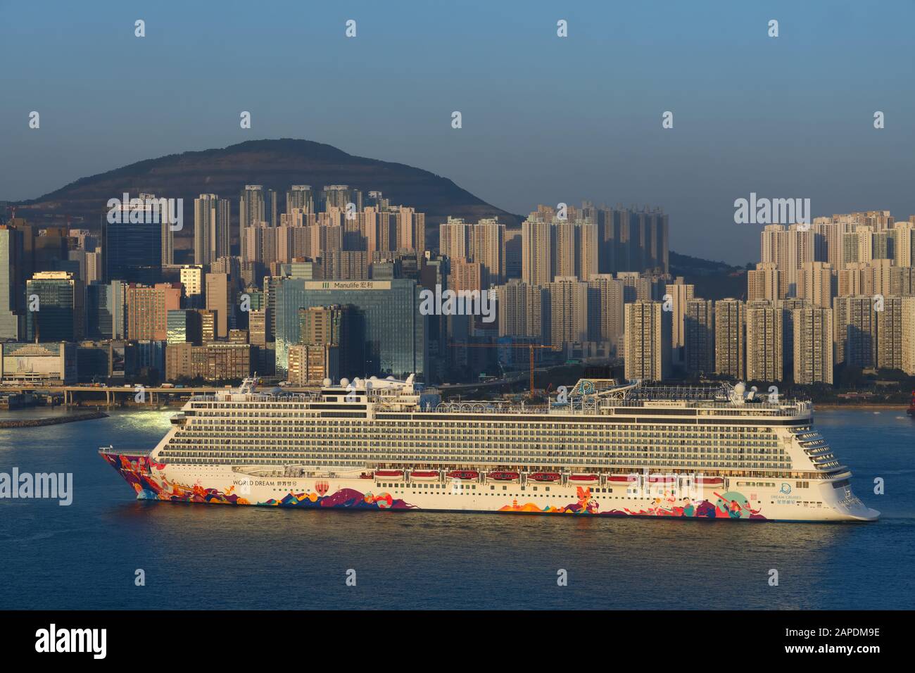 Der Kreuzfahrtschiff "World Dream", der in Kowloon Bay, Hongkong, China ankommt, während die Sonne am Abend untergeht. Stockfoto