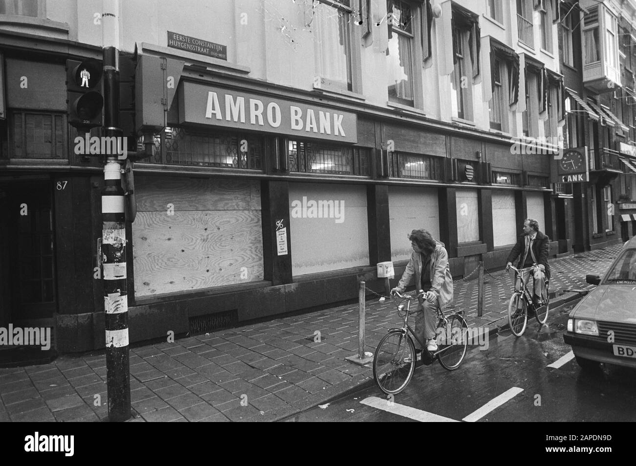 Verdutzte Fenster von Banken, nachdem die Fenster bei Krawallen eingeworfen wurden, in Amsterdam Beschreibung: Amrobank Overtoom, 1e Constantijn van Huygenstraat Datum: 13. Oktober 1982 Standort: Amsterdam, Noord-Holland Schlüsselwörter: Bankgebäude, Radfahrer Stockfoto