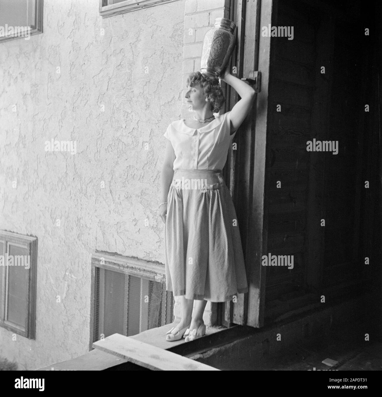 Israel 1948-1949 Beschreibung: Anonyme Frau posiert in stehender Position mit einer Metallvase auf dem Kopf an einer Wand vor einer Wohnung im Bau Datum: 1948 Ort: Israel Schlagwörter: Fotografien, Fotomodelle, posieren Stockfoto