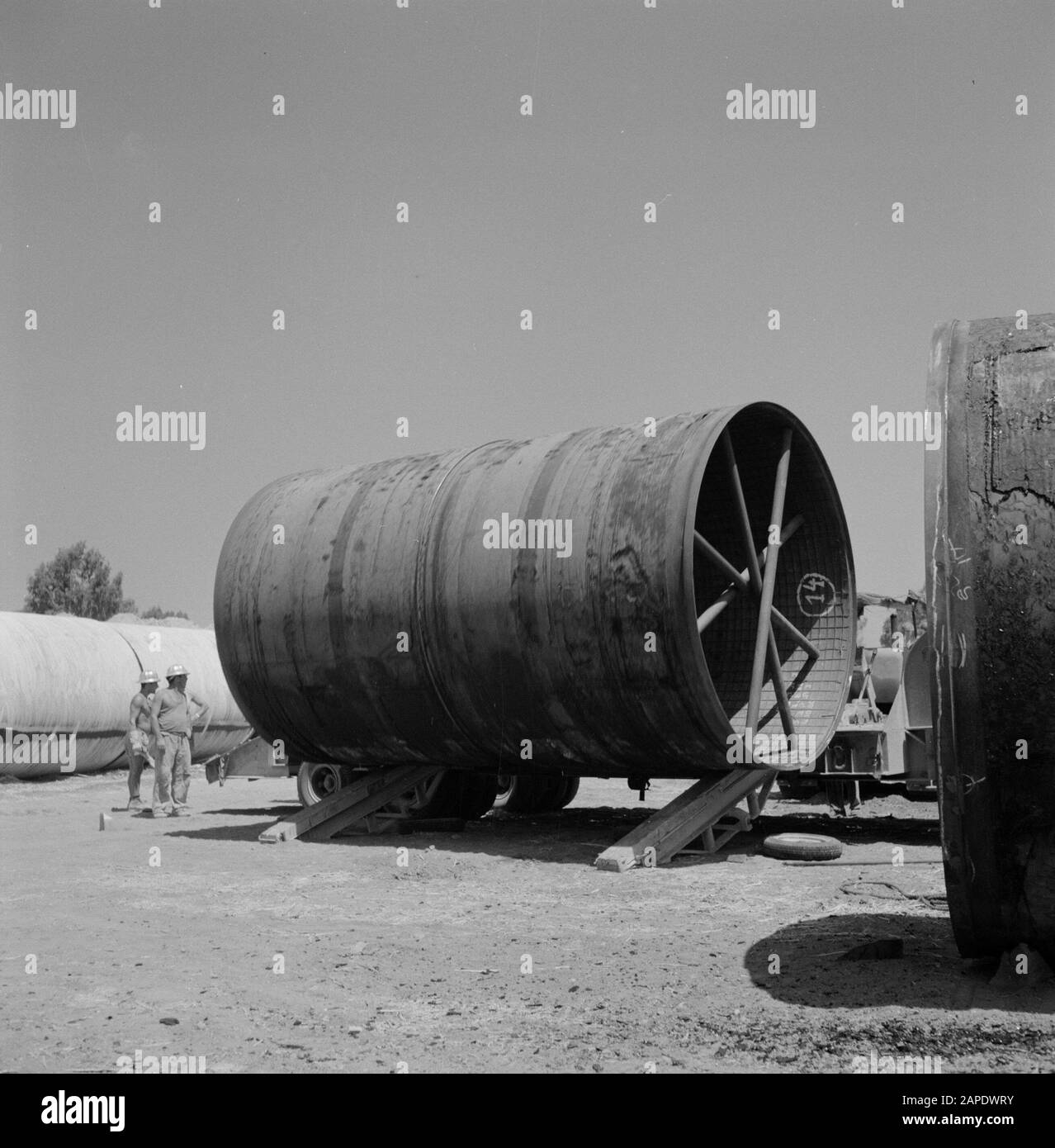 Arbeiter eines LKW mit einem Rohr, das vom Wagen gerollt und in einem Bewässerungsprojekt in der Negev-Wüste verwendet wird Datum: 1. Januar 1960 Standort: Israel, Negev Schlüsselwörter: Bewässerungsarbeiten, Rohre, Streben Stockfoto
