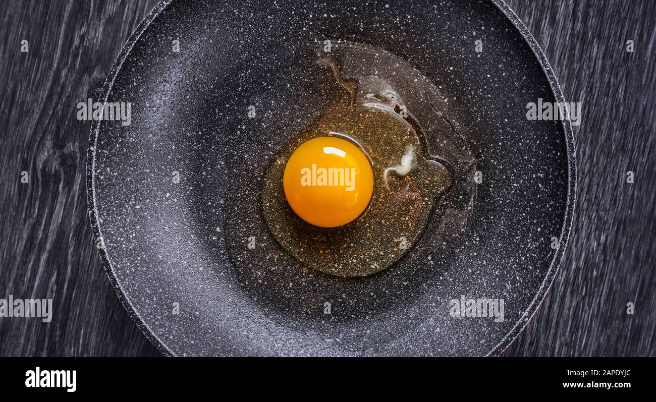 Ein rohes Ei in der Mitte einer Antihaftpfanne, symmetrisches Bild. Stockfoto