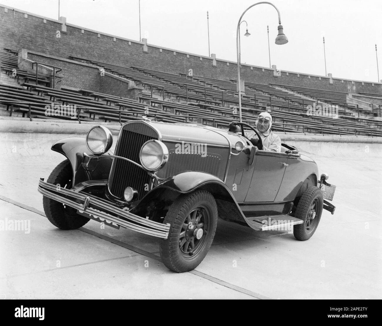 Olympiastadion und Stadionbuurt, Amsterdam Beschreibung: Autofahrer Van Marle fährt in seinem 2-sitzigen Chrysler Cabriolet entgegen dem Uhrzeigersinn ins Olympiastadion in Amsterdam-Zuid vor leeren Tribünen. Datum: 1932 Ort: Amsterdam-Zuid, Noord-Holland Schlüsselwörter: Autos, Autofahrer, Rennwagen, Rennen, Stadien, steht persönlicher Name: Marle, [...] vorbei Stockfoto