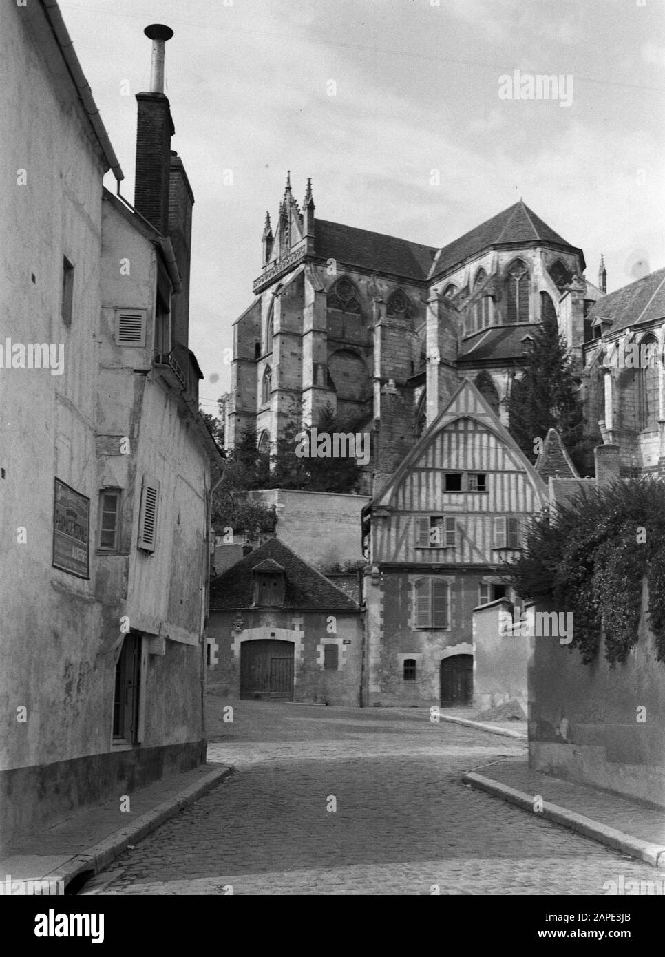 Reise nach Frankreich Beschreibung: Auxerre. Blick auf den Chor und das Südquerhaus der ehemaligen Abteikirche St. Germain-l'Auxerrois mit einem spätmittelalterlichen Haus mit einem Fachwerk im zweiten Stock und der oberen Fassade Datum: September 1935 Standort: Auxerre, Frankreich Schlagwörter: Fassaden, Gotik, Kirchenbauten, Tore, Stadtplastiken, Straßen, Häuser Stockfoto