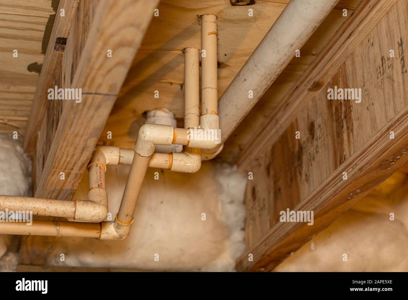 Alte PVC-Kunststoff-Wasserversorgungsleitungen unter dem Haus im Kriechraum installiert. Warmes und kaltes Wasserleitungssystem für Waschbecken und Dusche im Bad Stockfoto