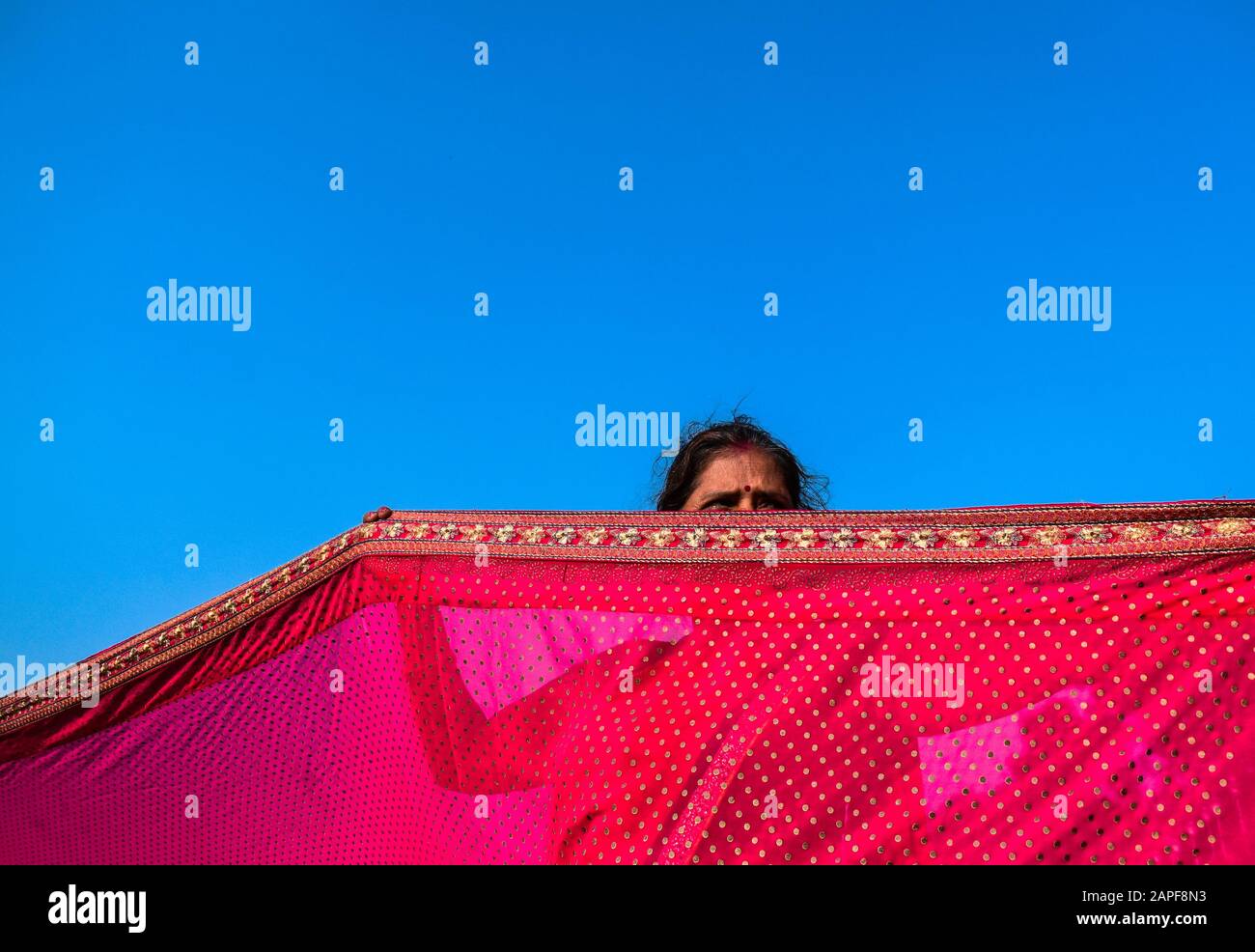 Eine Frau trocknet ihre Saree durch Sonnenlicht in einem Transitlager in Kolkata, Indien. Stockfoto