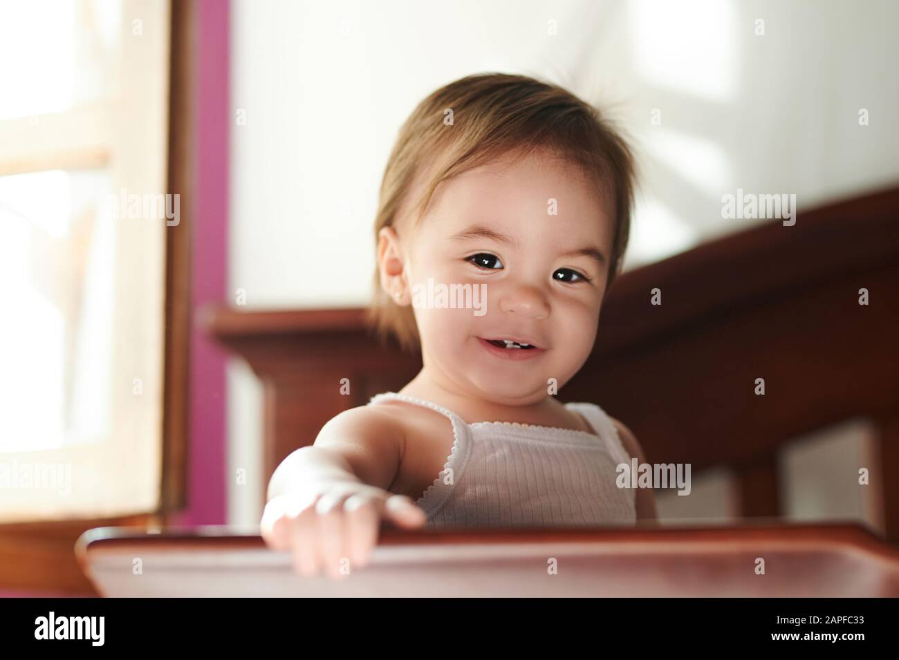 Süßes kleines Mädchen steht auf dem Bett und sieht in der Kamera aus Stockfoto