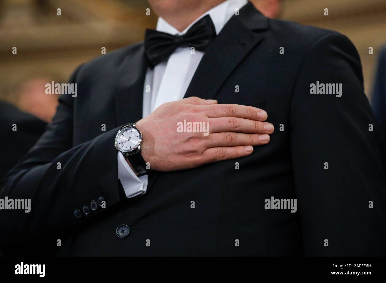 Details mit einem Mann in Tuxedo, der seine Hand am Herzen hält, während er die Nationalhymne hört. Stockfoto
