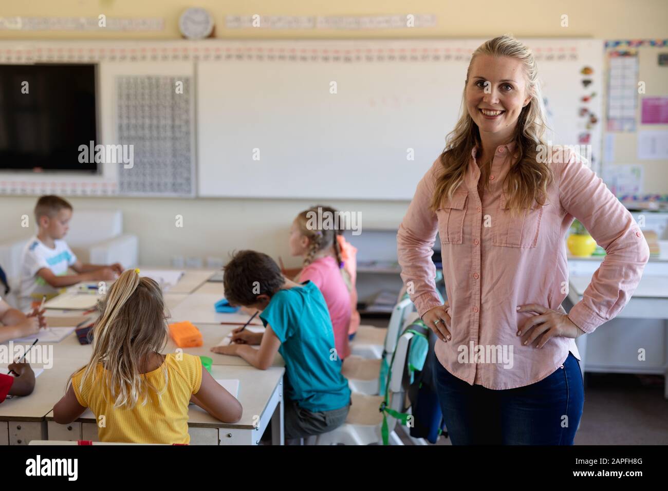 Lehrerin mit langen blonden Haaren, die in einem Klassenzimmer stehen Stockfoto
