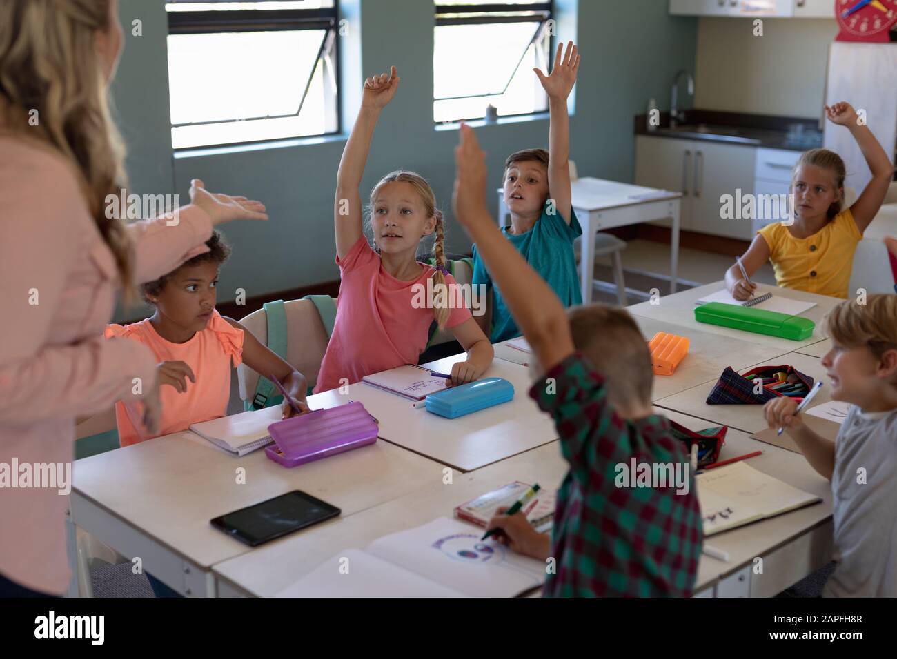 Gruppe von Schulkindern, die ihre Hände in einem Schulunterricht heben Stockfoto