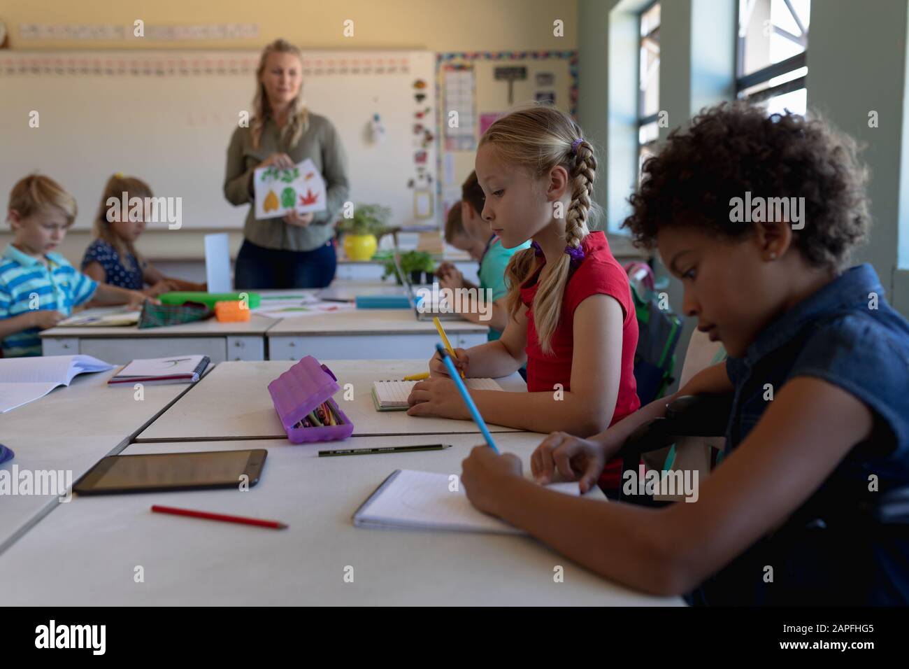 Schulmädchen sitzen an Schreibtischen in einem Schulunterricht Stockfoto