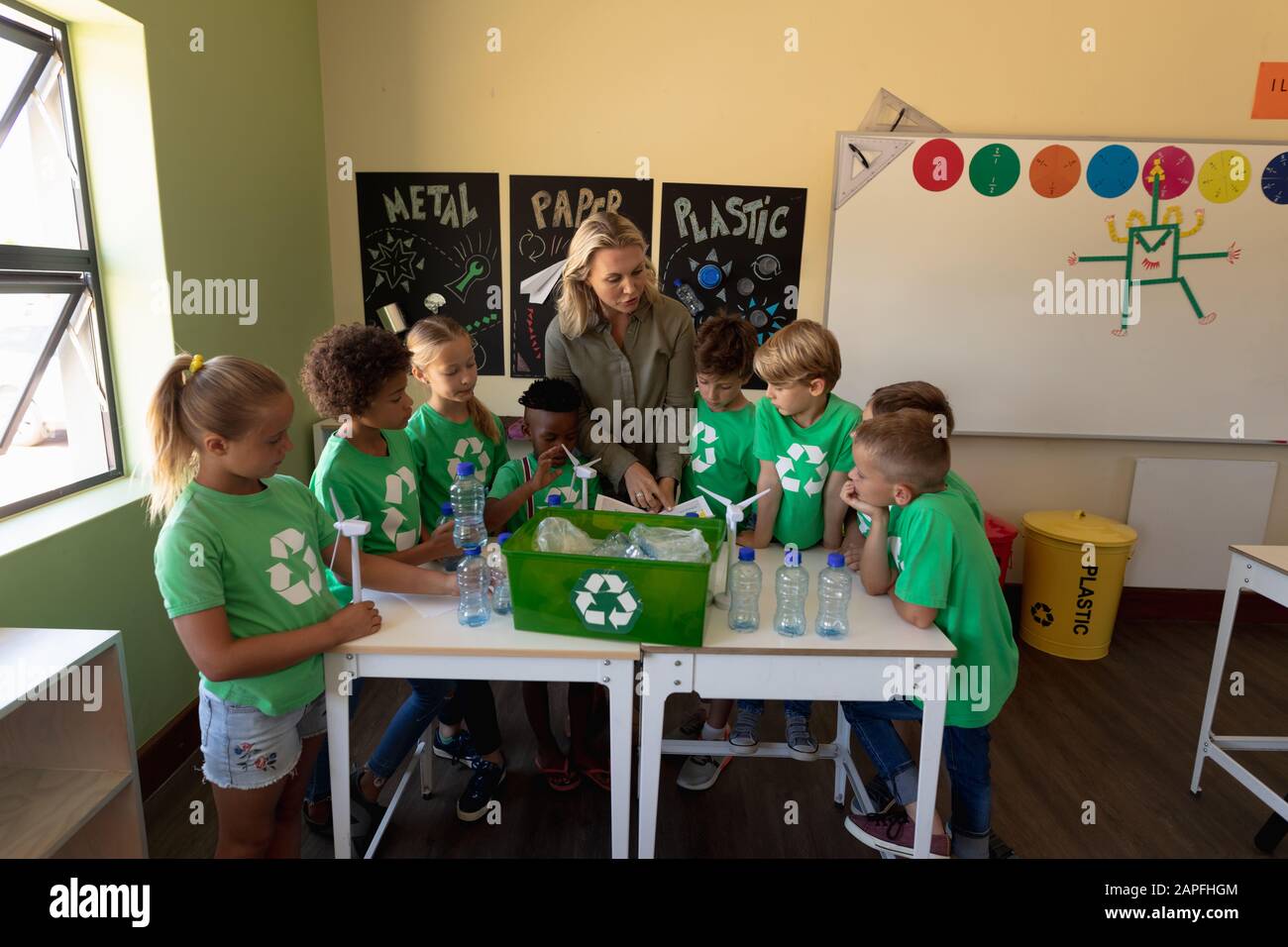 Schulleiterin mit einer Gruppe von Schülern, die grüne T-Shirts mit weißem Recycling l tragen Stockfoto