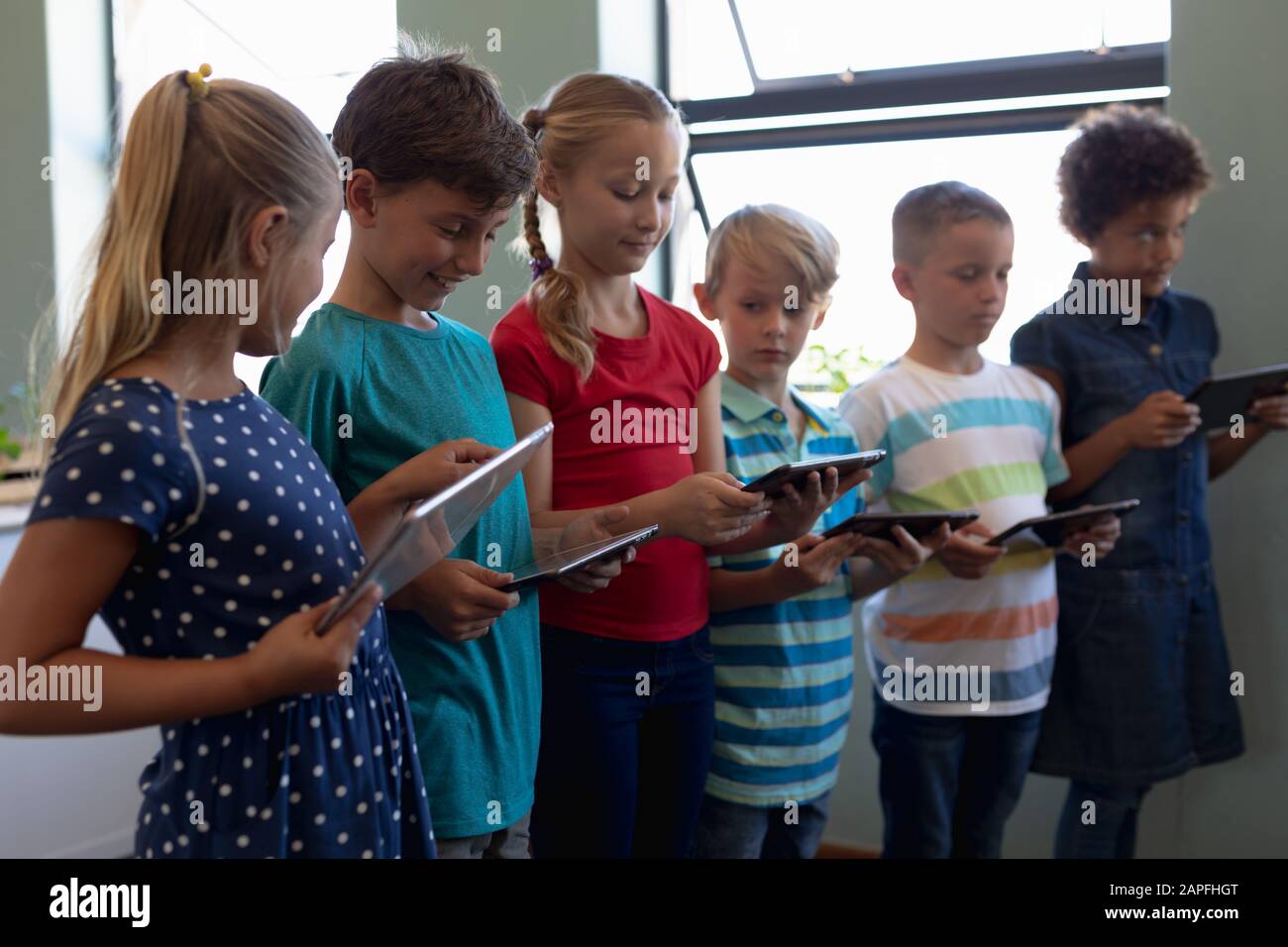 Gruppe von Schülern, die in einer Reihe stehen und Tablet-Computer verwenden Stockfoto