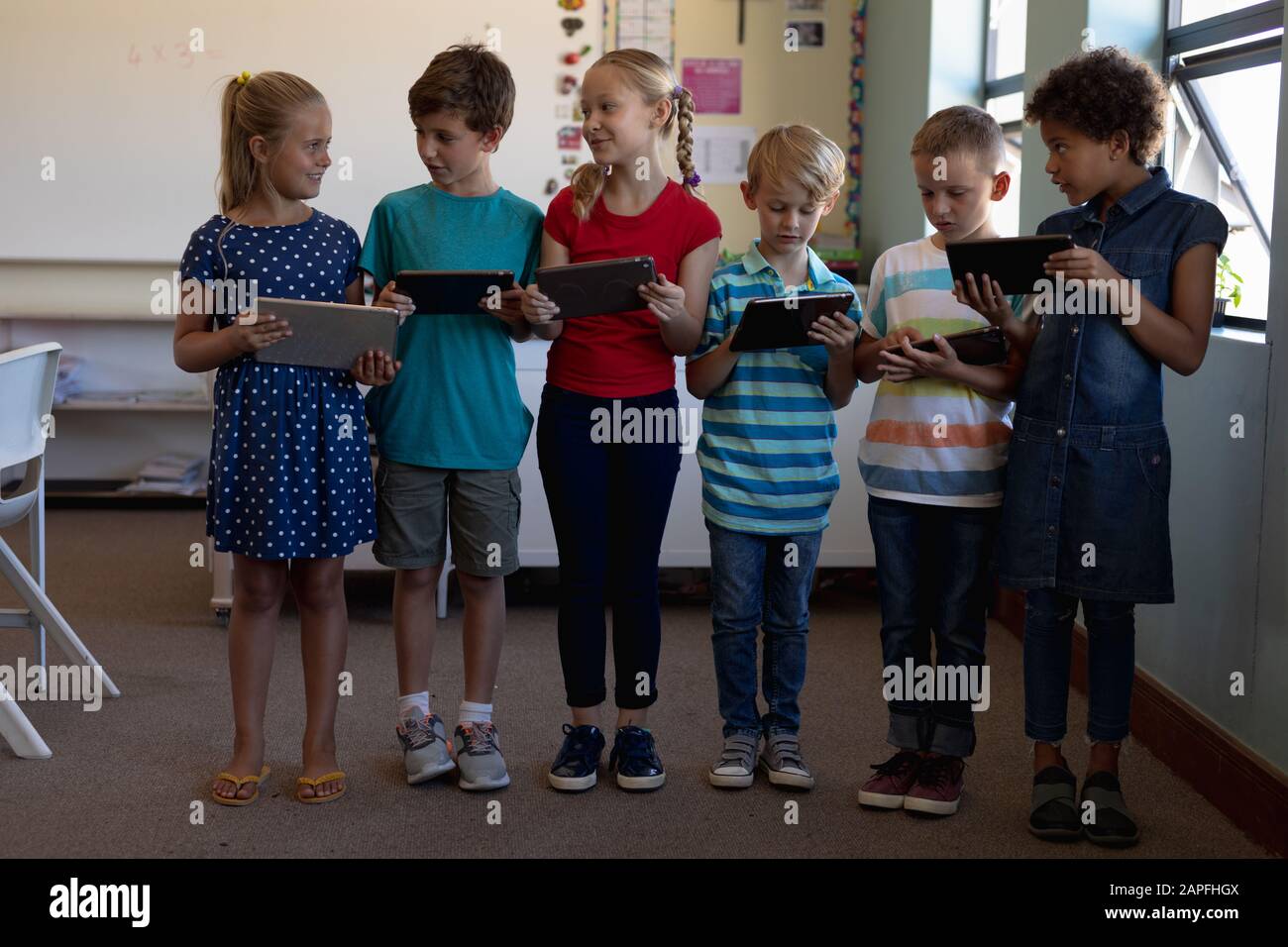 Gruppe von Schülern, die in einer Reihe stehen und Tablet-Computer verwenden Stockfoto
