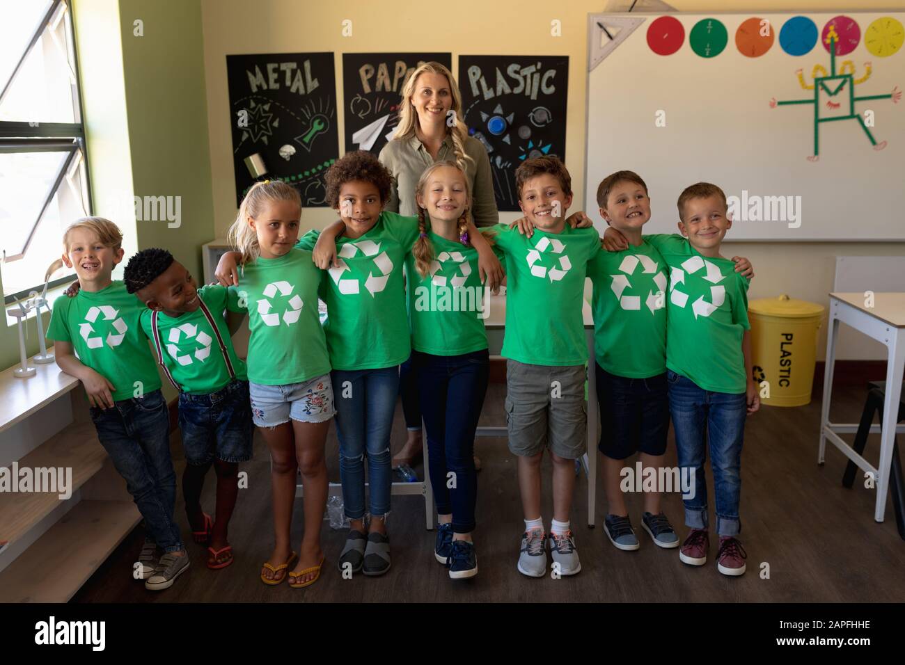 Schulleiterin mit einer Gruppe von Schülern, die grüne T-Shirts mit weißem Recycling l tragen Stockfoto