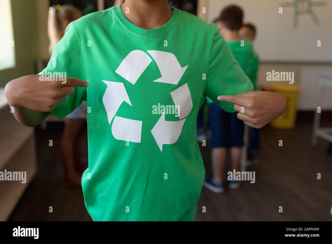 Schuljunge, der ein grünes T-Shirt mit einem weißen Recycling-Logo trägt Stockfoto