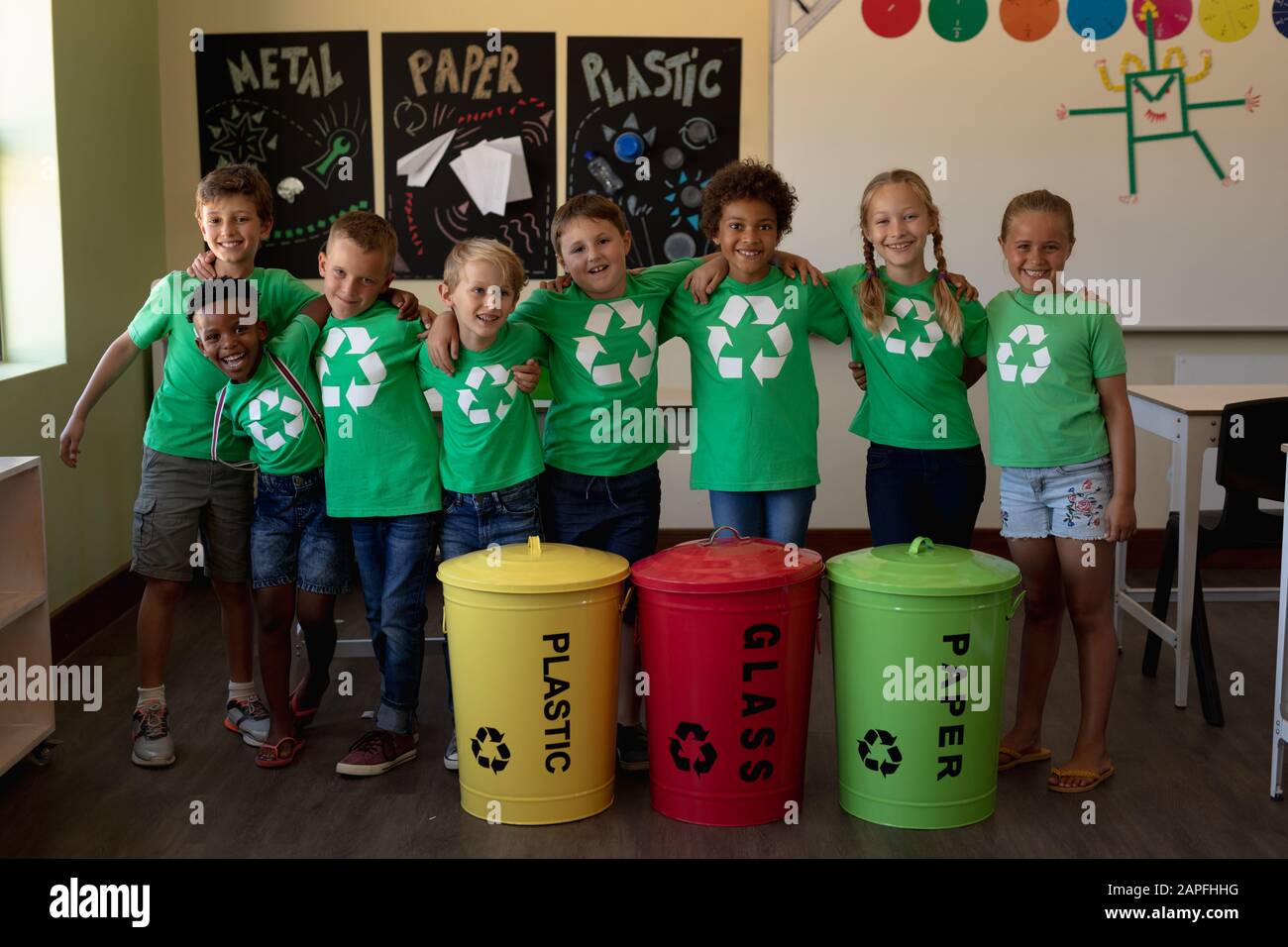 Gruppe von Schulkindern, die farbcodierte Recycling-Mülltonnen und -Beutel in einer Grundschulklasse halten Stockfoto