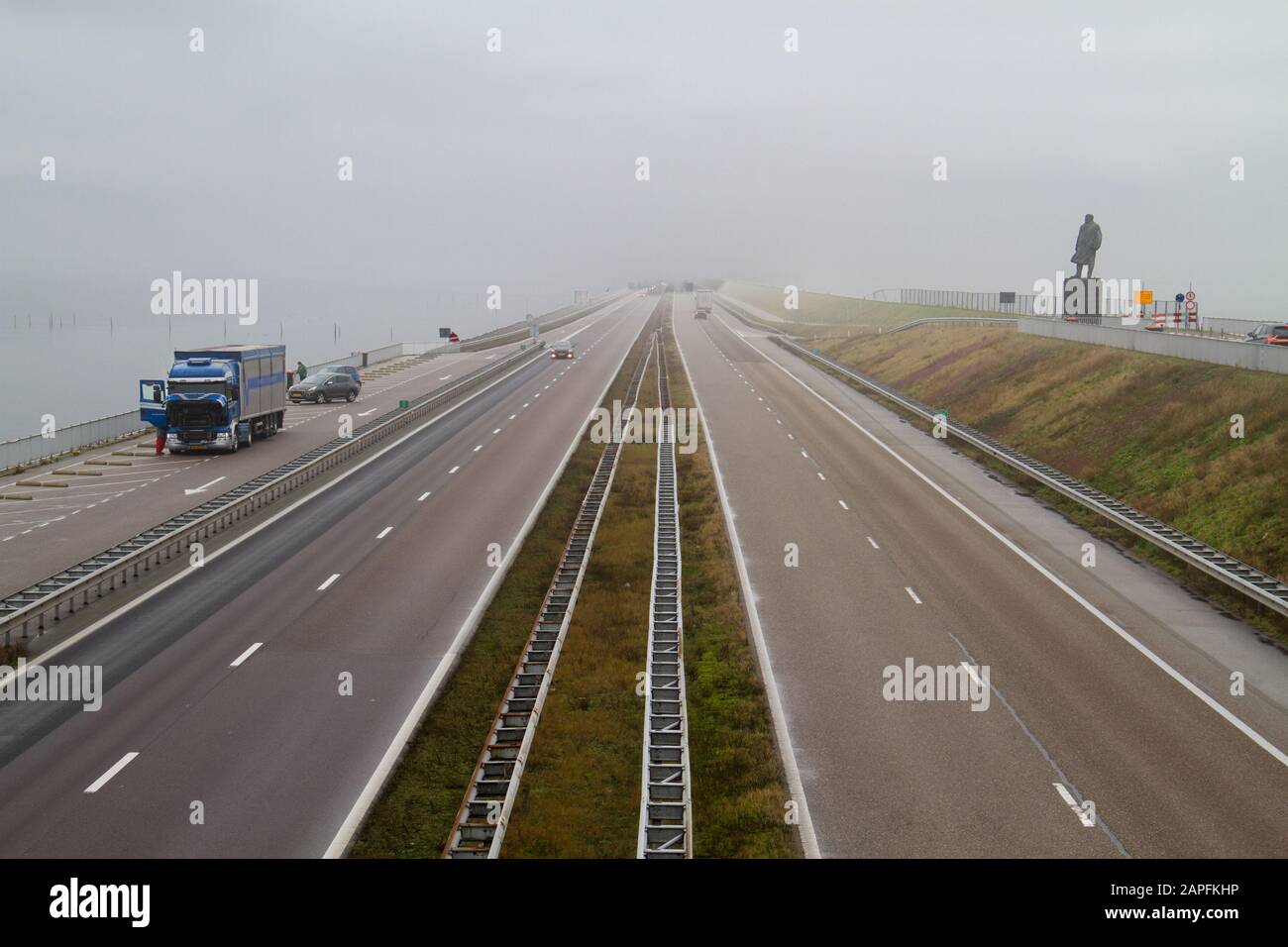 Verkehr auf dem Afsluitdijk, einem riesigen Deich zwischen dem IJsselmeer en de Waddenzee in den Niederlanden, rechts eine Statue von Cornelis Lely Stockfoto