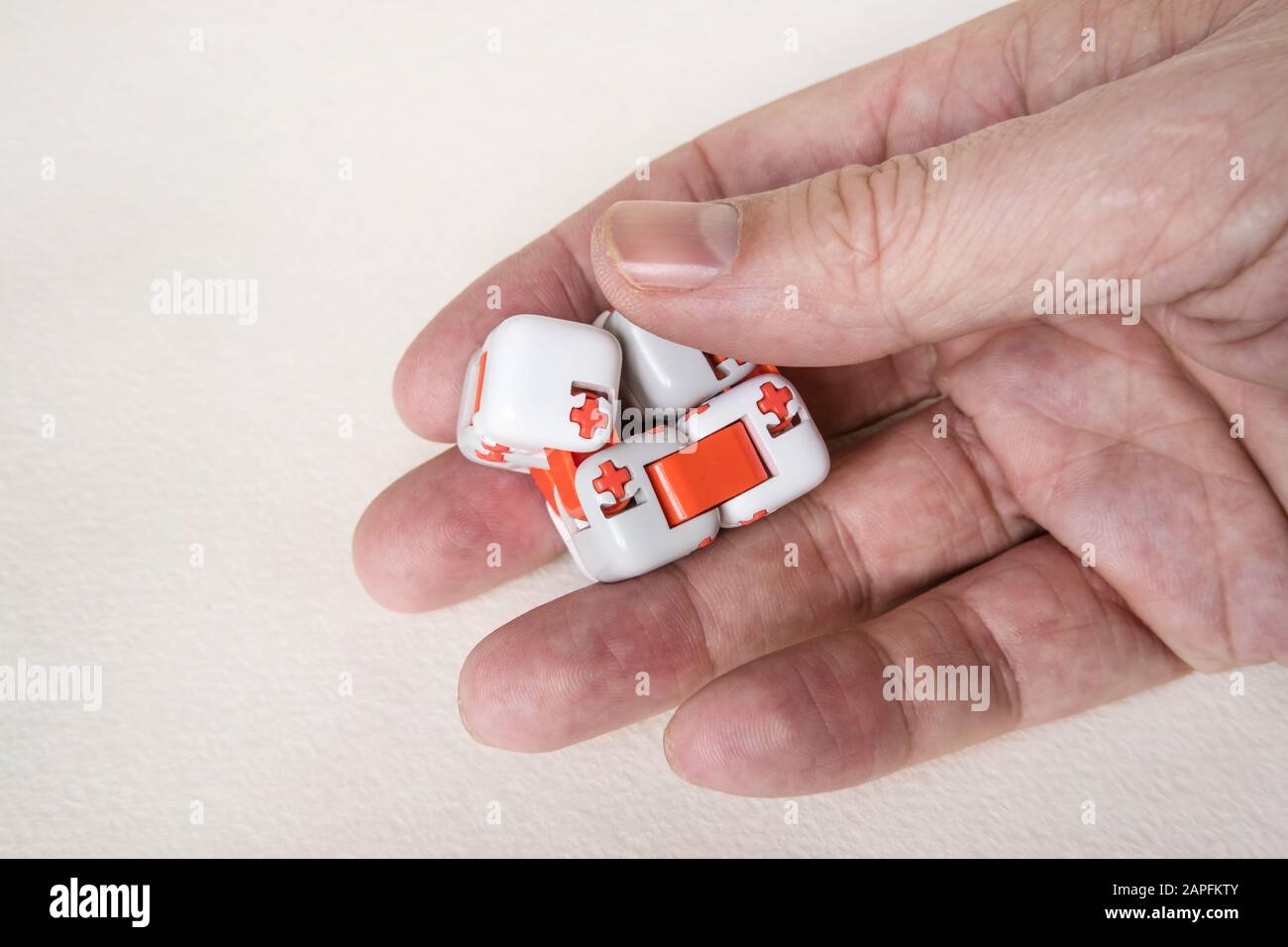 Bunte Finger Antistress fidget Würfelspielzeug in der Hand auf weißem Hintergrund. Entwicklung von feinen motorischen Fähigkeiten der Finger von Kindern Stockfoto