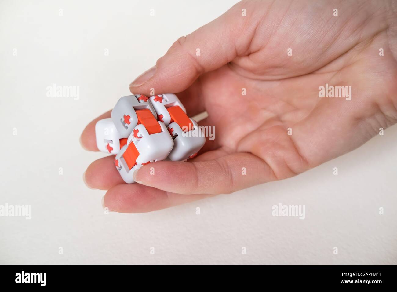 Bunte Finger Antistress fidget Würfelspielzeug in der Hand auf weißem Hintergrund. Entwicklung von feinen motorischen Fähigkeiten der Finger von Kindern Stockfoto
