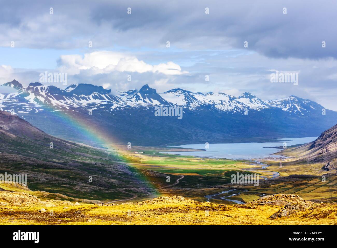 Wunderschöne isländische Landschaft mit Fjord und Regenbogen auf schneebedeckten Bergen Stockfoto
