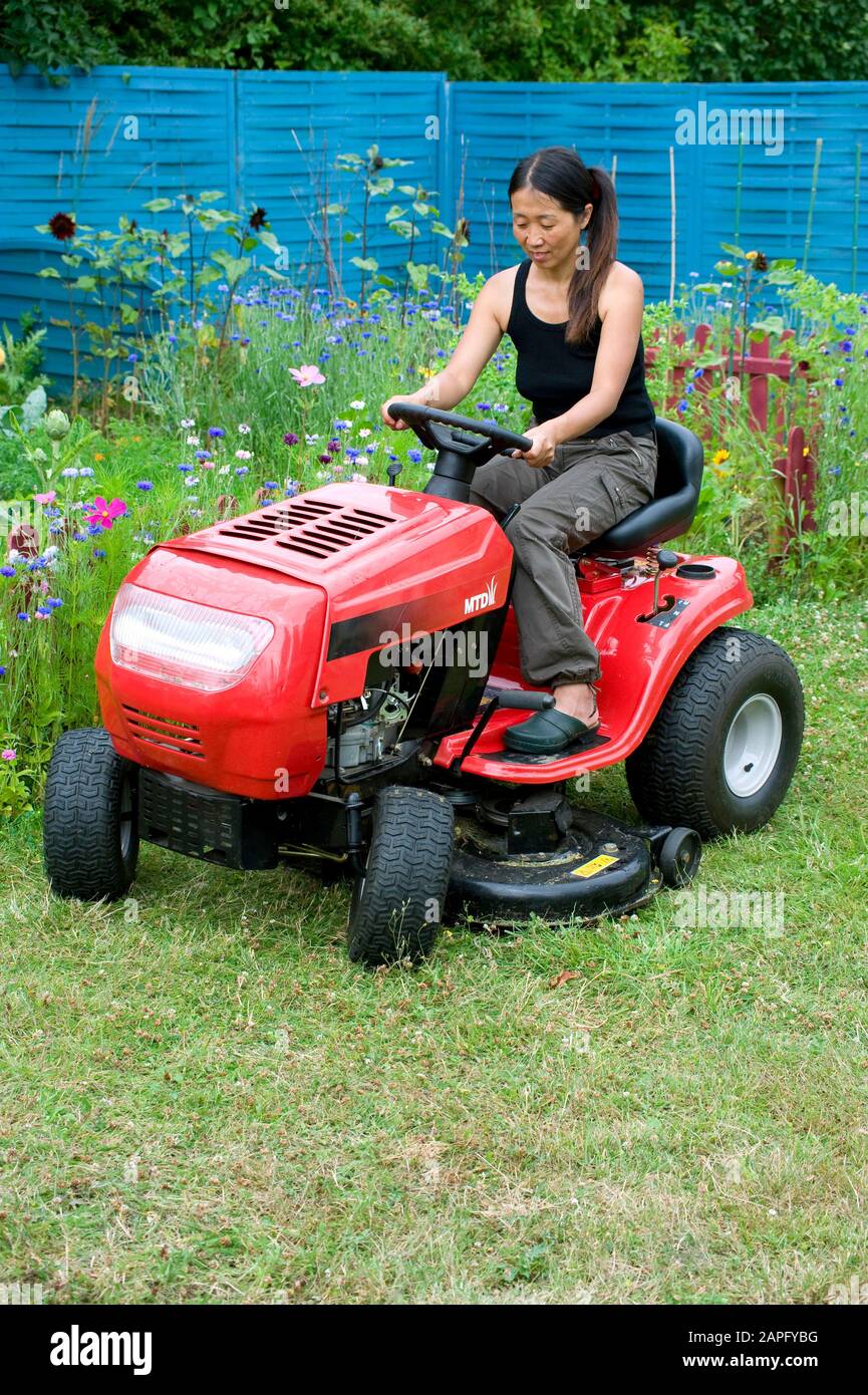 Frau, die den Rasen auf einem Reitmäher mäht Stockfoto