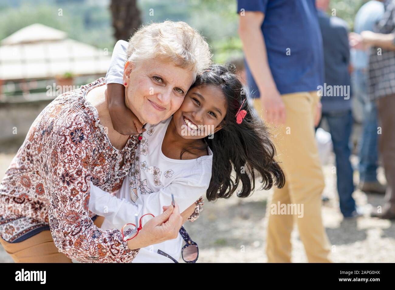 Glückliches Mädchen, das eine ältere Frau bei Familienzusammenkunft umarmte, Florenz, Italien Stockfoto