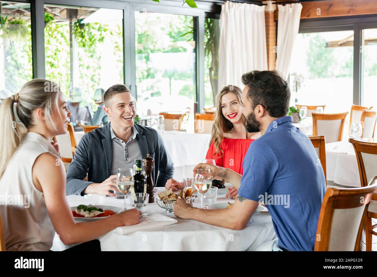 Freunde sprechen am Esstisch im Restaurant Stockfoto