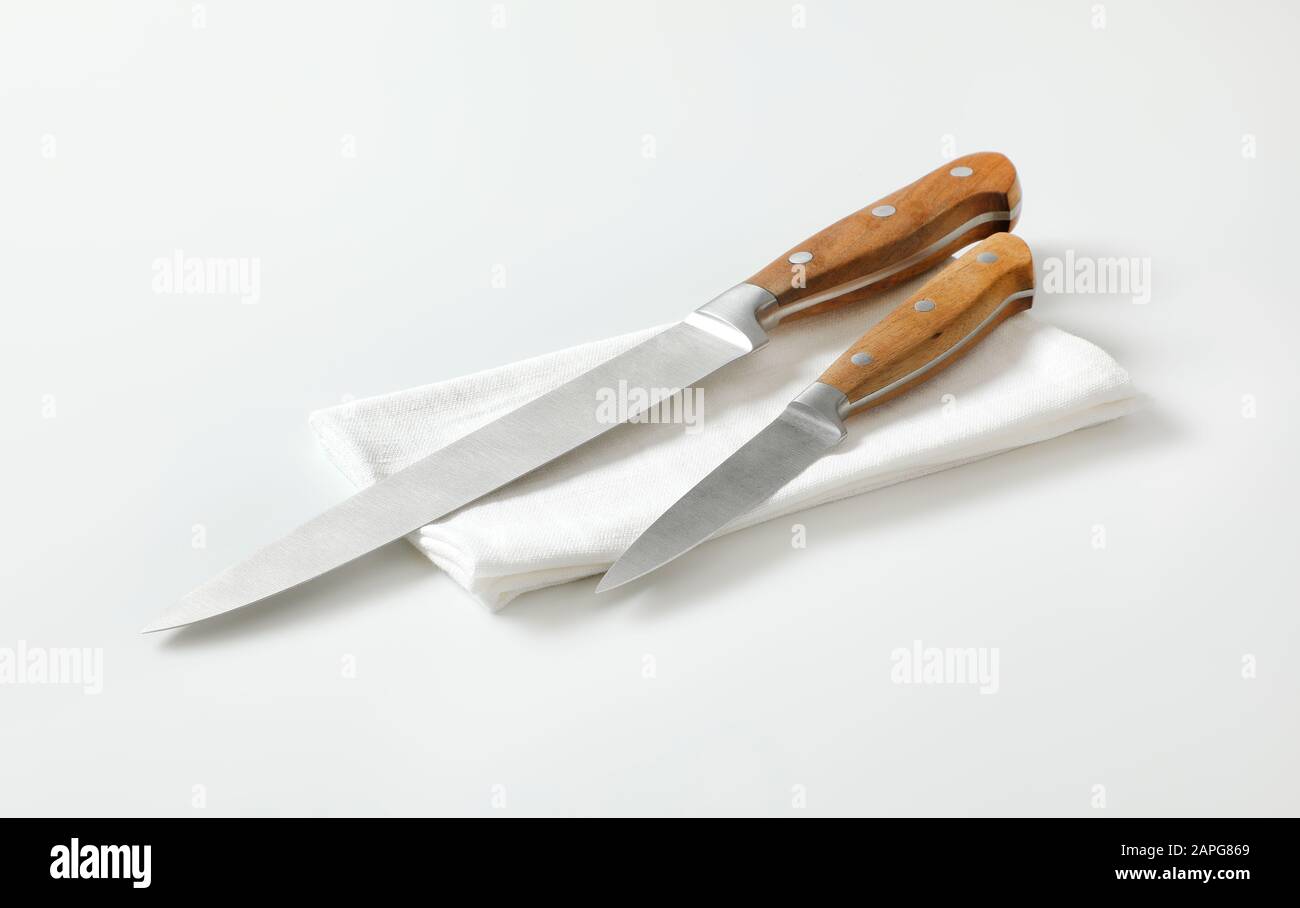 Küchenmesser und Trennmesser auf weißer Serviette Stockfoto