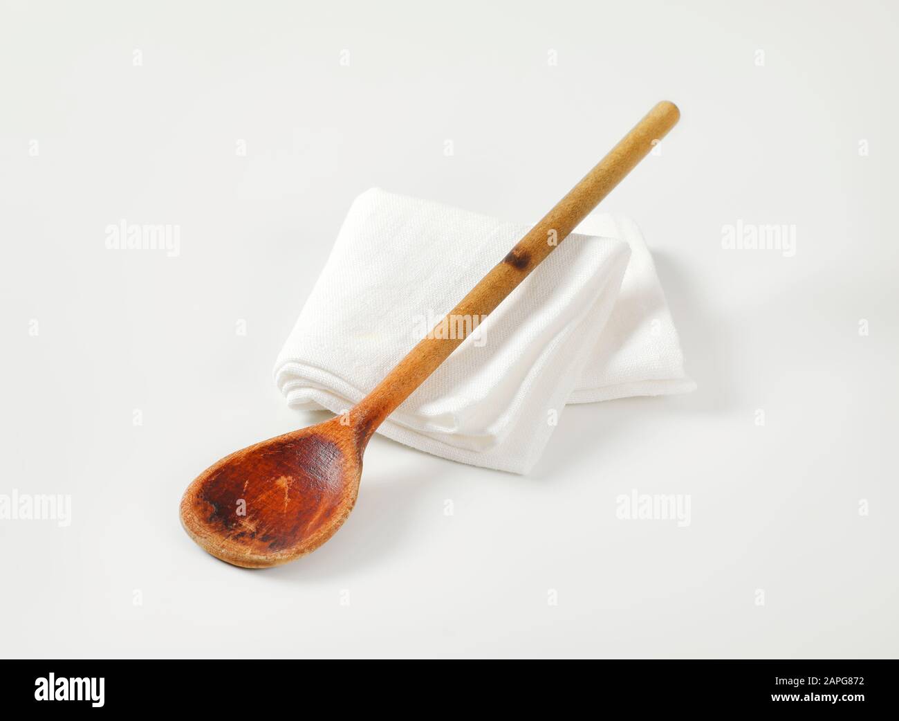 Alter Kochlöffel aus Holz (rührend) auf weißer Serviette Stockfoto