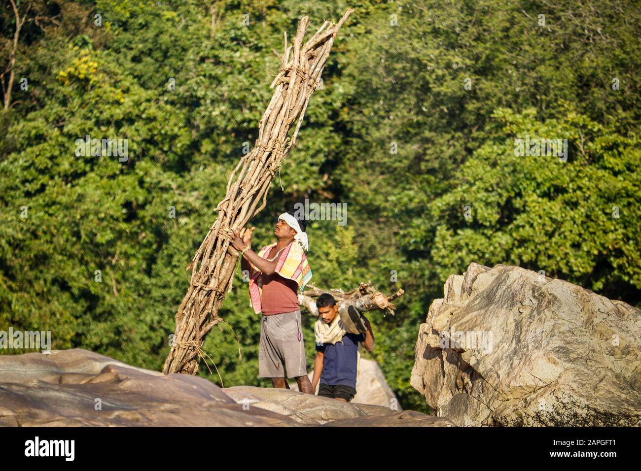 Ländliche Menschen bringen ein Bündel Holz aus dem Wald durch den Felsen Stockfoto