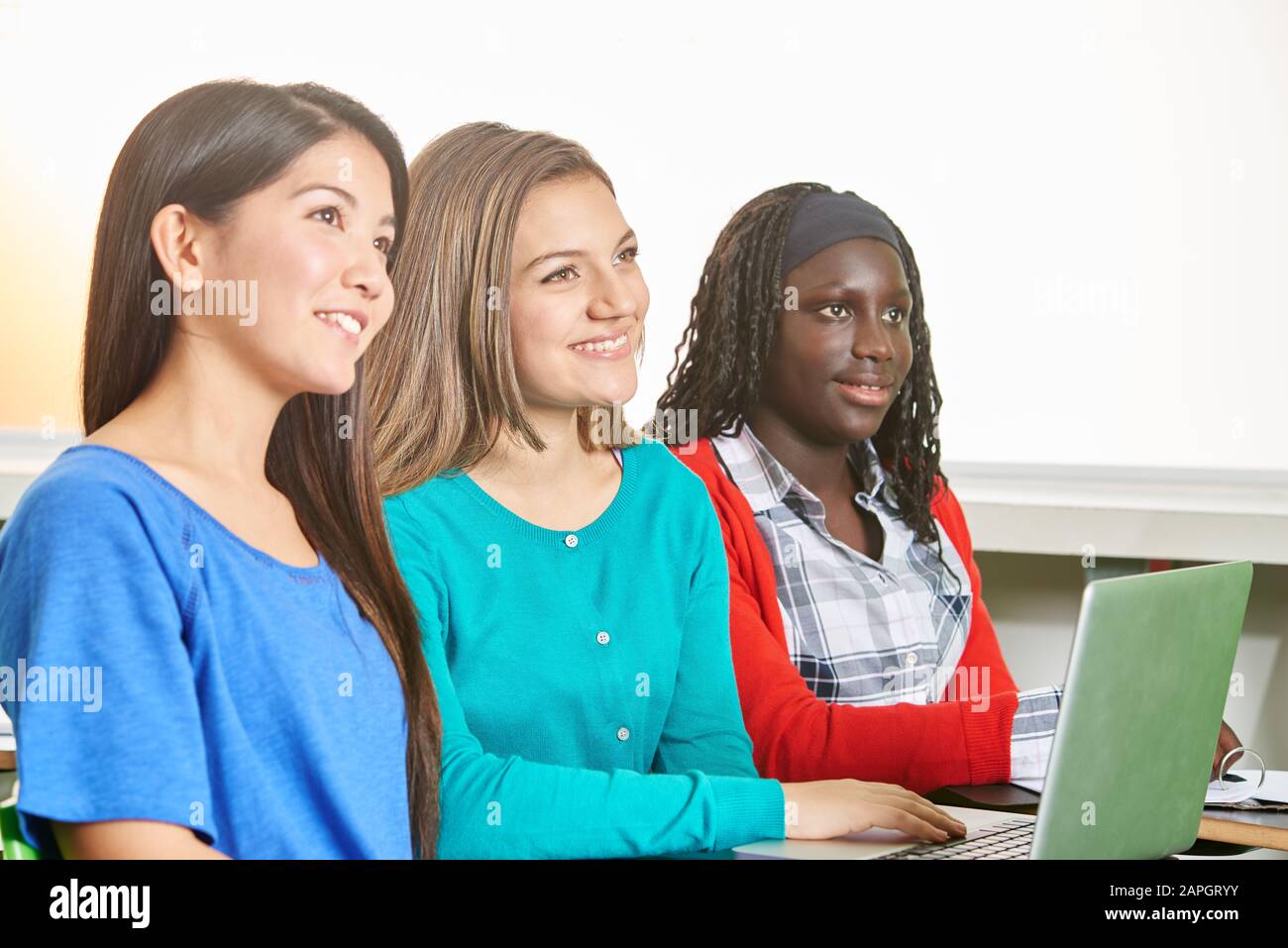 Glückliche Mädchen, die in der Schule mit einem Laptop lernen Stockfoto
