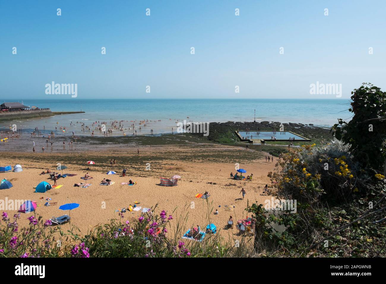 Menschen sonnen sich und Kinder spielen am Strand, natürliches Meerespool in den Felsen an der Viking Bay, Broadstairs, Kent, Großbritannien Stockfoto