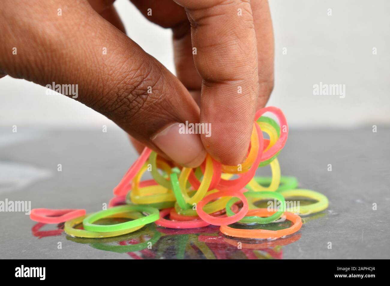 Mehrfarbige Gummibänder von Hand. Gummibänder und Finger. Gummibänder aus der Hand geworfen. Stockfoto