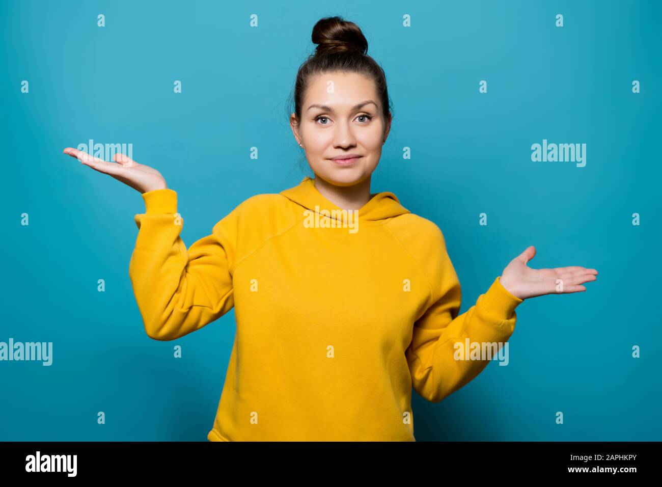 Ein Mädchen in einem Sweatshirt zeigt ihre Handflächen nach oben und zeigt eine Auswahl oder Waage, eine Seite unter der anderen Stockfoto