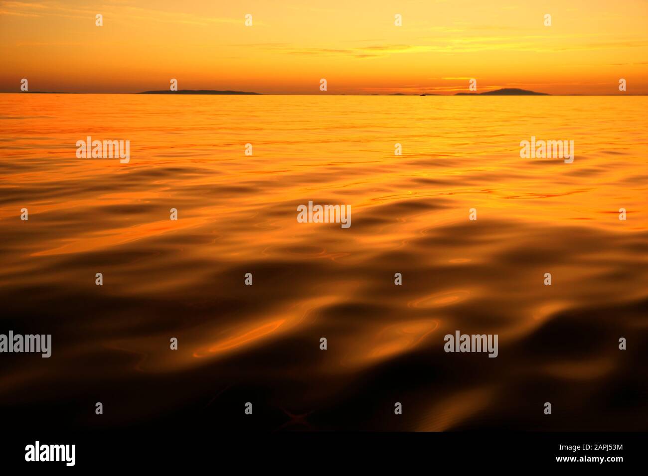 Leuchtend orangefarbener Sonnenuntergang mit unechter bunter Wasseroberfläche und Himmel auf einem roten Planeten. Abstrakter Naturhintergrund mit Meeresoberfläche und Blick wie Stockfoto