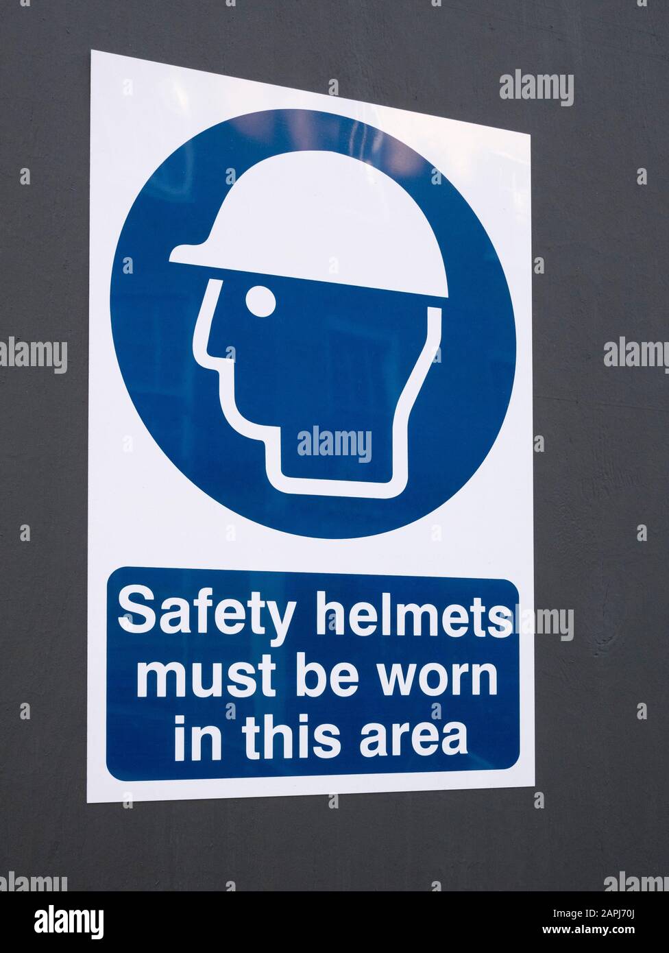 Britische Baustelle / Baustelle Warnschild für Gesundheit und Sicherheit an Fechten, Baustellenzaun befestigt. Warnsymbol für die Baustelle mit Hut Stockfoto
