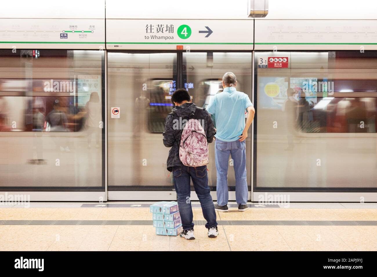 Zug Hongkong - Passagiere auf dem Bahnsteig, während ein Zug am Bahnhof Mong Kok der MTR Hongkong - Mass Transit Railway in Hongkong Asia anfährt Stockfoto
