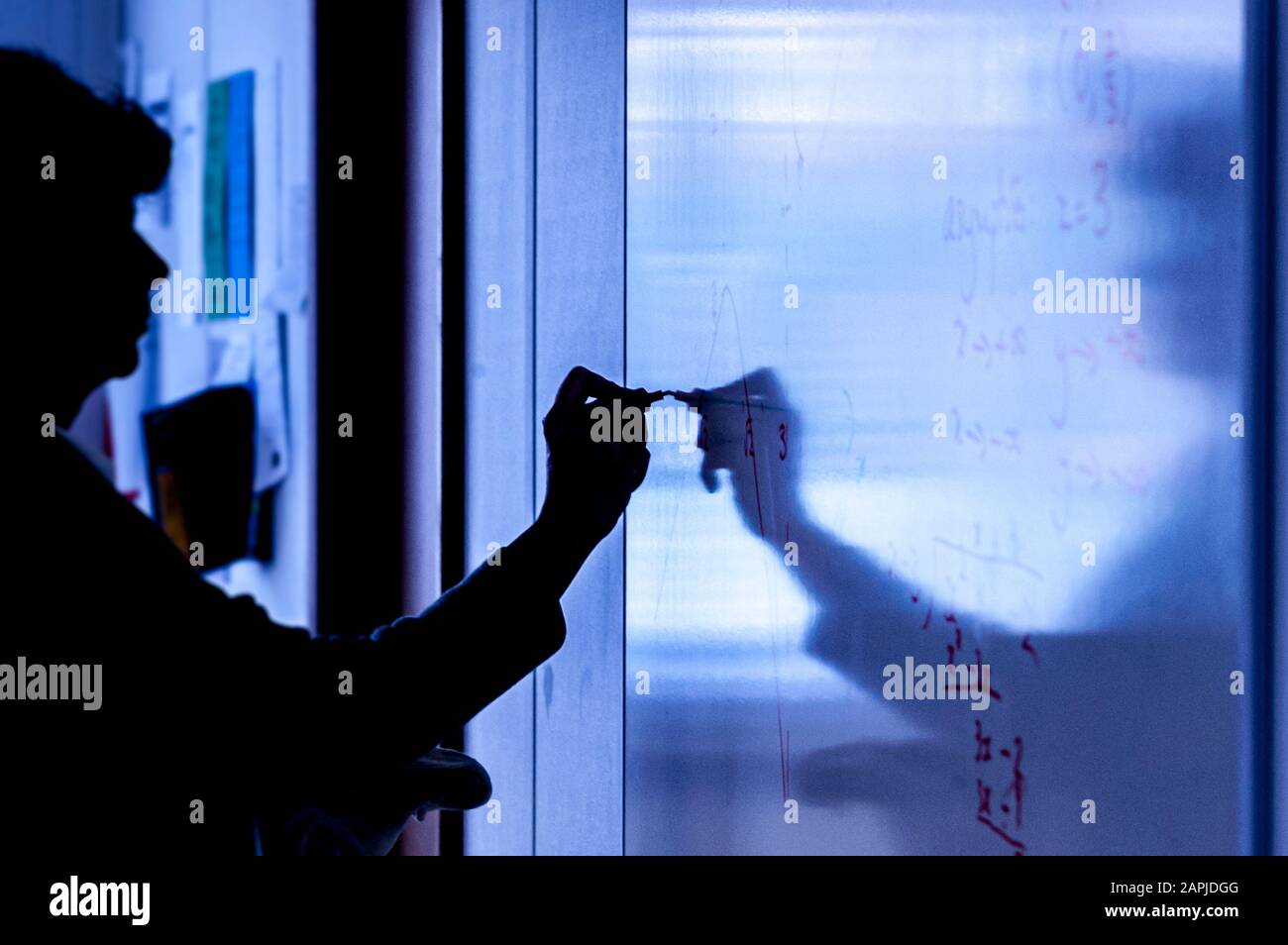 Silhouette des Lehrers, der auf dem Whiteboard im Klassenzimmer schreibt Stockfoto
