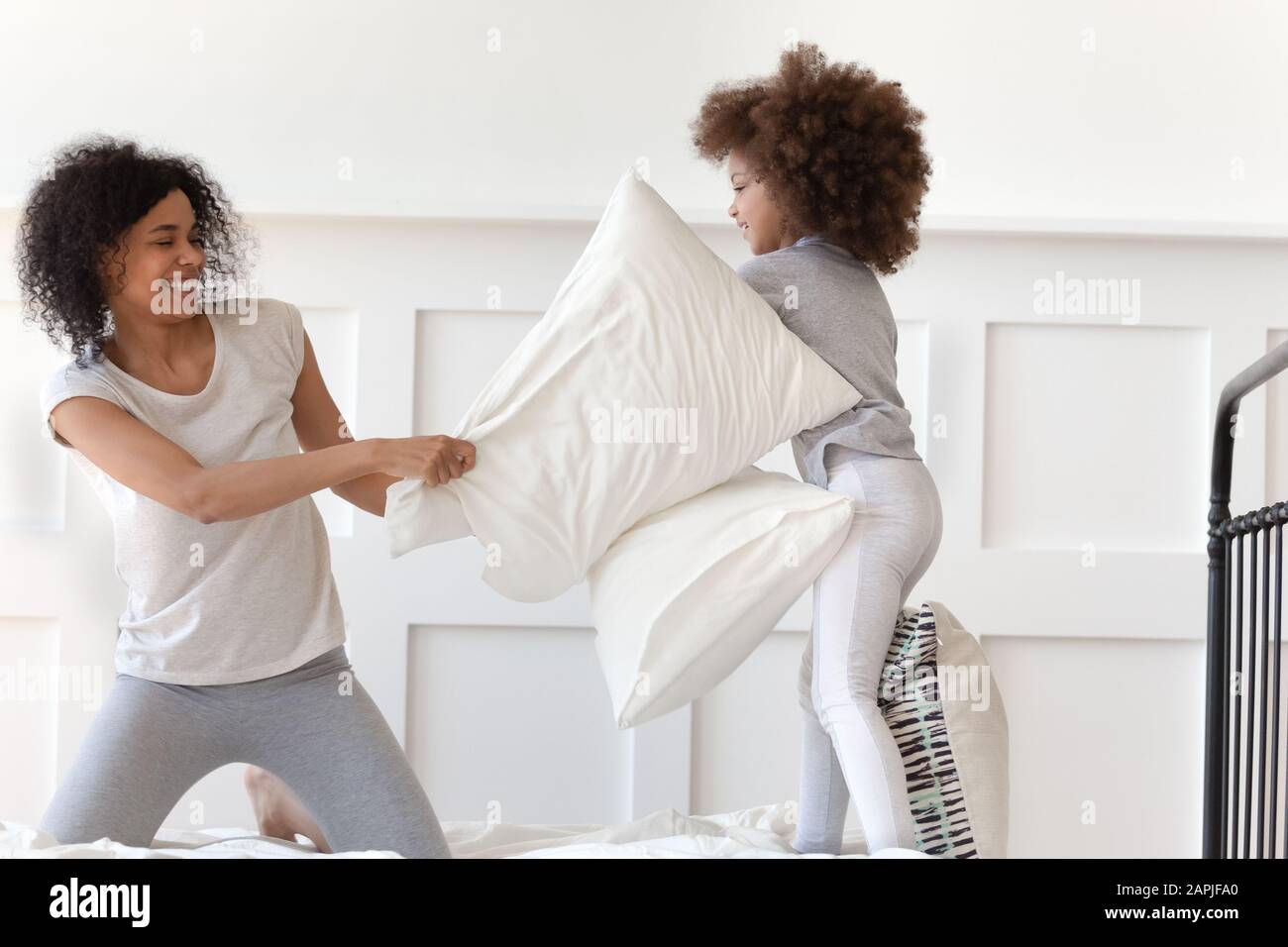 Afrikanische Mutter hält Kopfkissen, die mit kleiner Tochter kämpft Stockfoto