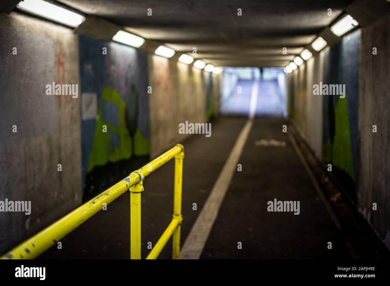 Eine schlecht beleuchtete U-Bahn oder Unterführung mit dem Schwerpunkt auf dem gelben Geländer und einem verschwommenen Hintergrund Stockfoto