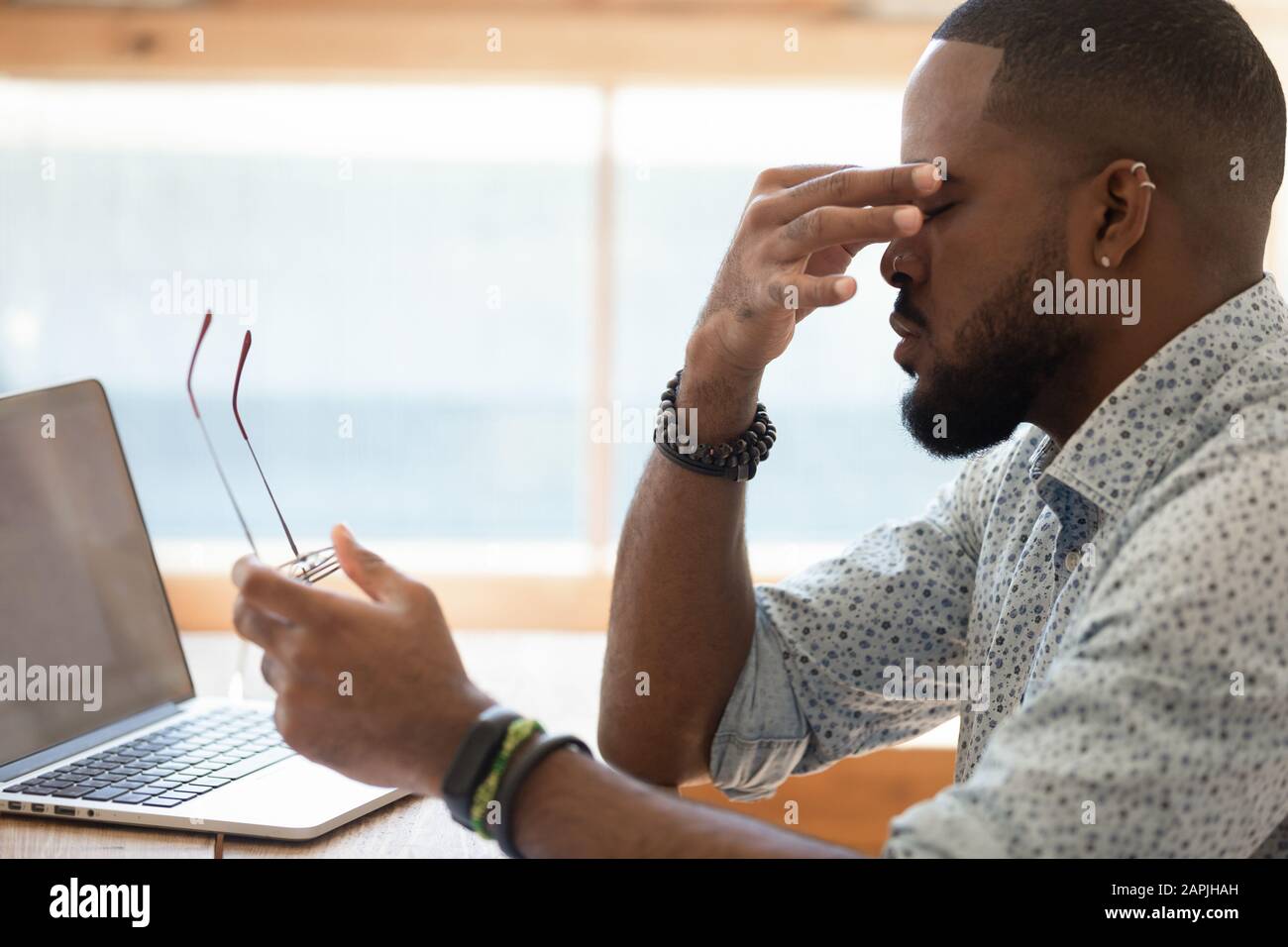 Afrikanischer Kerl nahm Brille ab, die Nasenbrücke reibt, wodurch die Augenbelastung verringert wurde Stockfoto