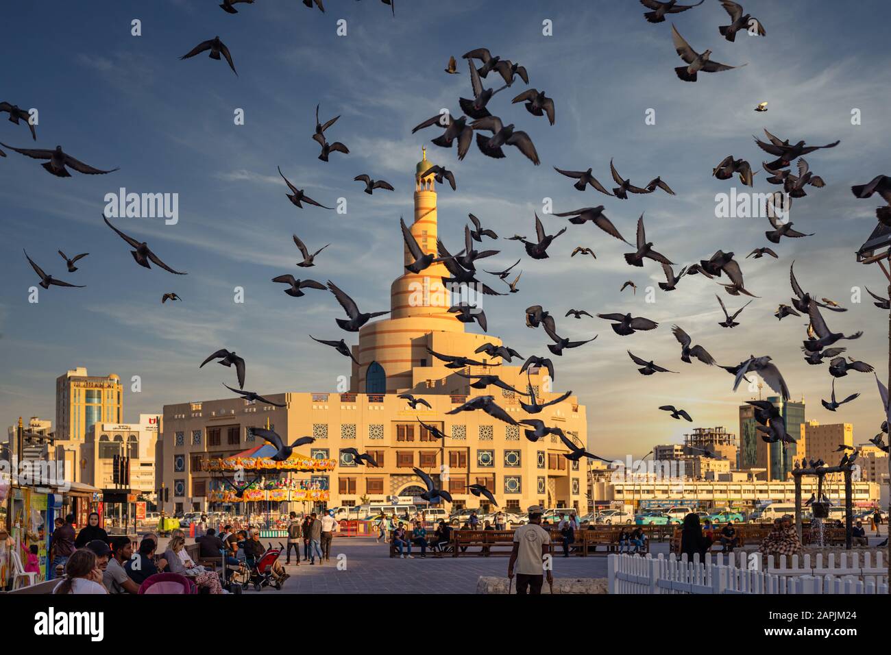 Doha, Qatar-Januar 21.2020: Al-Fanar Qatar Islamic Cultural Centre Tageslichtansicht mit Tauben, die in den Himmel fliegen, im Vordergrund und Wolken im Himmel Stockfoto