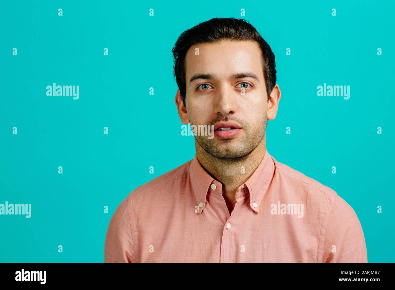 Porträt eines jungen erwachsenen Mannes ernst, isoliert auf blauem Studiohintergrund Stockfoto