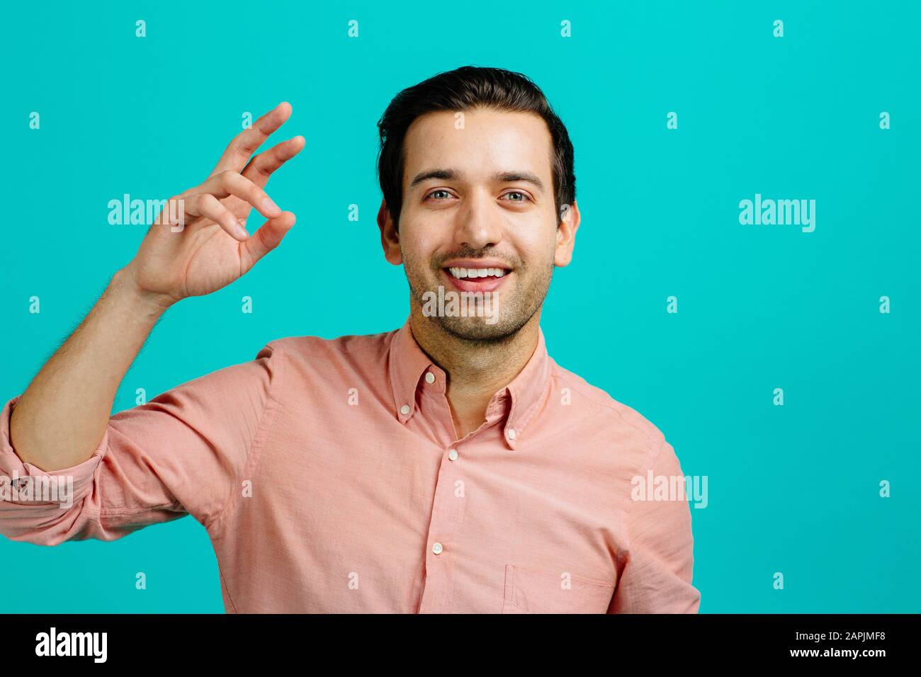 Porträt eines jungen erwachsenen Mannes lächelnd, isoliert auf blauem Studiohintergrund Stockfoto